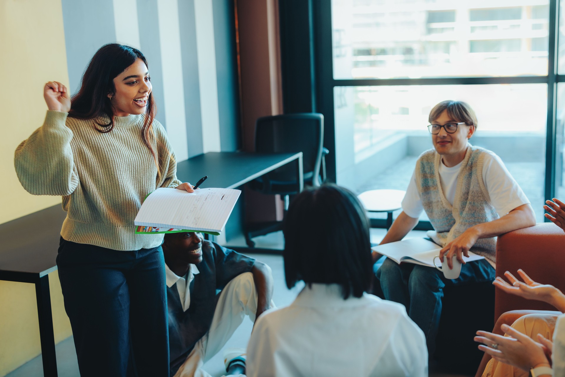 Confident student presenting a project to classmates in a modern classroom setting with attentive audience